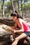 Young brunette girl reading map sitting on log