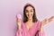 Young brunette girl using facial exfoliating cleaner celebrating achievement with happy smile and winner expression with raised