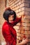 Young brunette girl in vintage romantic red dress near the wall