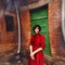 Young brunette girl in vintage romantic red dress near the wall