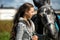 Young brunette with gray horse in a field in summer