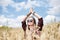 Young brunette hippie woman, wearing boho style clothes, sitting in the middle of wheat field with blue sky, meditating, thinking