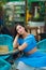 A young brunette with long hair in a blue crop top sits thoughtfully at a table in an outdoor cafe