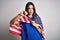 Young brunette patriotic woman with blue eyes wearing united states of america flag with angry face, negative sign showing dislike