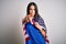 Young brunette patriotic woman with blue eyes wearing united states of america flag pointing with finger to the camera and to you,