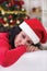 Young brunette sitting next Christmas tree looking lonely