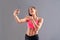 Young brunette smiling sporty woman making selfie and shows biceps on grey background, studio shoot.