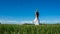 Young brunette spanish woman doing Vriksasana tree yoga pose in a field next to a lake with long curly hair Space in sky