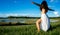 Young brunette spanish woman doing warrior 2 yoga pose in a field next to a lake with long curly hair