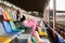 Young brunette sportswoman, wearing black top, pink leggings and sneakers, sitting on colorful seats on stadium tribune, relaxing