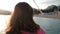 Young brunette stands on the coast of lake looking on the sunset.