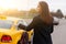 Young brunette stopping taxi on road in autumn