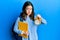 Young brunette student woman holding alarm clock skeptic and nervous, frowning upset because of problem