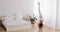 Young brunette in white bedroom doing yoga exercises, standing on the wooden floor near the window. Side view.