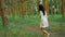 Young brunette in white dress walking in the forest