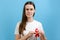 Young brunette woman 20s holds red ribbon, looking at camera, isolated on blue color background studio. Blood transfusion and