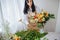 a young brunette woman in an apron in the process of creating a bouquet in the rustic style in her flower shop