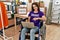 Young brunette woman as volunteer on donations stand sitting on wheelchair looking positive and happy standing and smiling with a