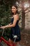 A young brunette woman of Asian appearance in a dark blue dress is standing next to a bicycle with a punctured wheel. there is a