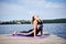 Young brunette woman with bare feet, wearing black and purple fitness outfit, doing cobra pose on violet yoga mat outside on