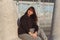 Young brunette woman in black hoodie sitting on a breakwaters.