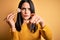 Young brunette woman with blue eyes eating salmon maki sushi using chopsticks pointing with finger to the camera and to you, hand