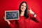 Young brunette woman with blue eyes holding blackboard with strong word message happy with big smile doing ok sign, thumb up with