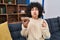 Young brunette woman with curly hair eating healthy whole grain cereals with spoon puffing cheeks with funny face