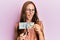 Young brunette woman cutting dollars with scissors for currency devaluation winking looking at the camera with sexy expression,