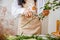 a young brunette woman florist in apron cuts leaves from the stems before starting to create a bouquet in her workshop