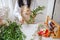 a young brunette woman florist in apron cuts leaves from the stems before starting to create a bouquet in her workshop