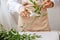 a young brunette woman florist in apron cuts leaves from the stems before starting to create a bouquet in her workshop