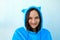 Young brunette woman in fluffy blue pajamas or cat costume on a blue pastel background