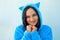 Young brunette woman in fluffy blue pajamas or cat costume on a blue pastel background