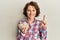 Young brunette woman holding bowl with pumpkin seeds smiling with an idea or question pointing finger with happy face, number one