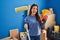 Young brunette woman holding roller painter painting new house sticking tongue out happy with funny expression