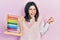 Young brunette woman holding traditional abacus screaming proud, celebrating victory and success very excited with raised arms