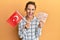 Young brunette woman holding turkey flag and liras banknotes smiling and laughing hard out loud because funny crazy joke