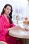 young brunette woman in kitchen wearing pink dressing gown with a cup of hot beverage coffee. tender woman portrait