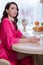 young brunette woman in kitchen wearing pink dressing gown with a cup of hot beverage coffee. tender woman portrait