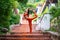Young brunette woman in orange sportswear doing the utthita ardha dhanurasana yoga pose