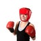young brunette woman in red boxing gloves and helmet making impact, looking at camera.