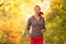 Young brunette woman running in autumn forest listening to mps m