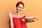 Young brunette woman with short hair holding carrot cake doing ok sign with fingers, smiling friendly gesturing excellent symbol