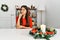 Young brunette woman sitting on the table on christmas serious face thinking about question with hand on chin, thoughtful about