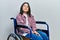 Young brunette woman sitting on wheelchair looking at the camera blowing a kiss on air being lovely and sexy