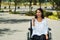 Young brunette woman sitting in wheelchair smiling with positive attitude, outdoors environment, physical recovery