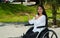 Young brunette woman sitting in wheelchair smiling with positive attitude, outdoors environment, physical recovery