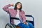 Young brunette woman sitting on wheelchair strong person showing arm muscle, confident and proud of power