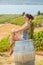 Young brunette woman sitting on a wooden wine barrel in front of a Okanagan vineyard.